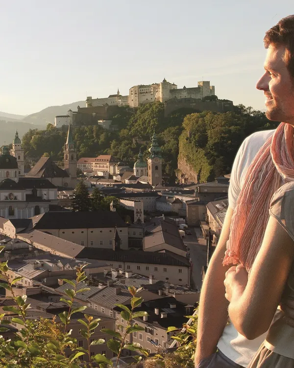 Paar genießt Panorama der Salzburger Altstadt und Festung Hohensalzburg bei Sonnenuntergang